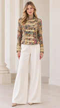 Full front view of model wearing Multi Floral tapestry military jacket with white wide-leg trousers