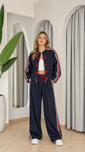 Front view of model wearing navy blue tracksuit set with red chinese knot buttons and side stripes