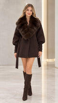 Front view of model wearing a chocolate brown belted coat with faux fur collar