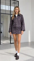 Full front view of model wearing black speckled dot zip-up jacket and matching mini skirt set