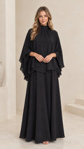 Front view of model wearing black mock neck cape overlay maxi dress