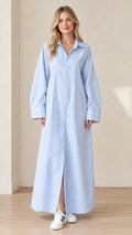 Full front view of a blonde model wearing a light blue and white striped maxi shirt dress with white sneakers