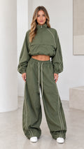 Front view of model wearing olive green cropped windbreaker jacket and wide leg parachute pants set