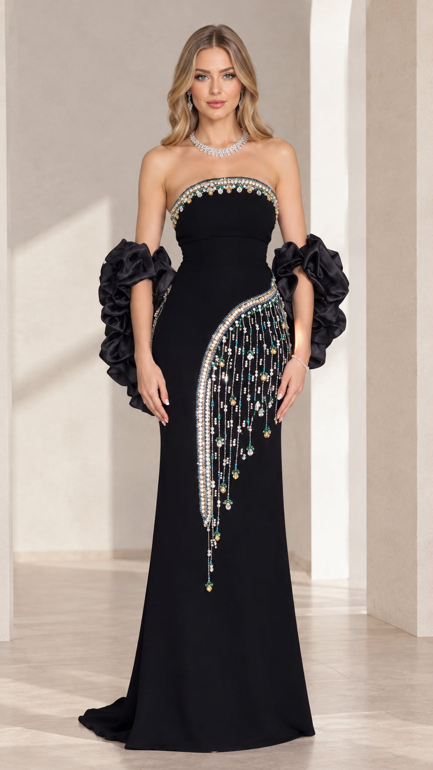 Front view of black strapless column gown with beaded fringe and ruffled arm cuffs