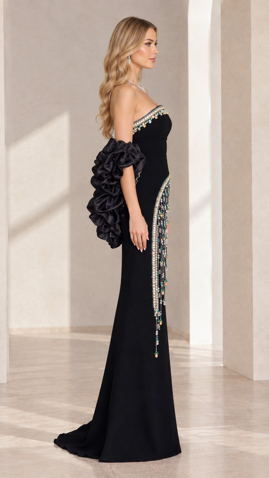 Side profile view of black strapless formal gown showing embellished hip fringe